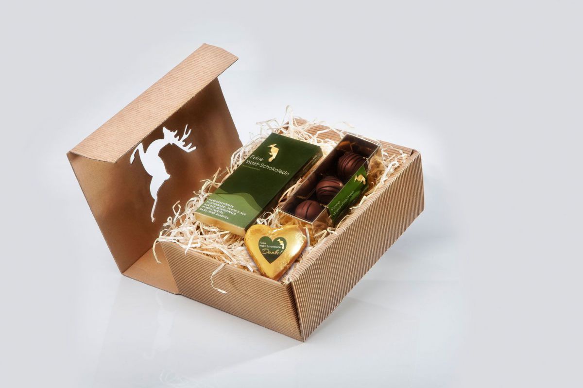 Eine schöne Kartonbox mit einem springenden Hirsch auf der Vorderseite. Darin eine Schokoladetafel, ein Schokoladeherz und drei Pralinen.