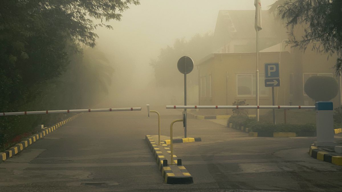 Eine Straße mit Schranken, auf der man kaum weit sieht, weil sie so Abgasverhangen ist.