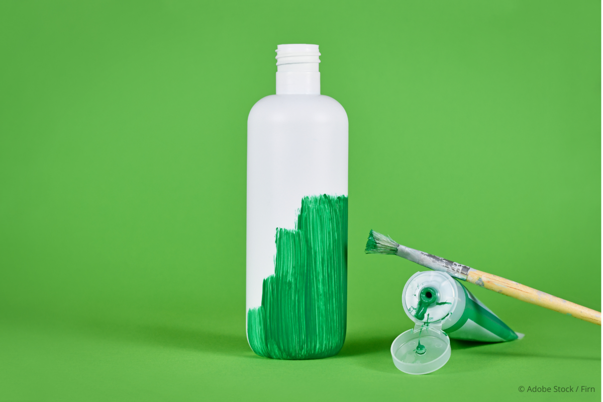Eine weiße Flasche vor grünem Hintergrund ist halb mit grüner Farbe bepinselt - Pinsel und Farbe liegen daneben.