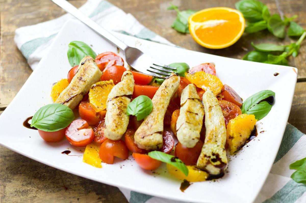 Ein Tomaten-Orangen-Salat mit veganen Hühnerstreifen.
