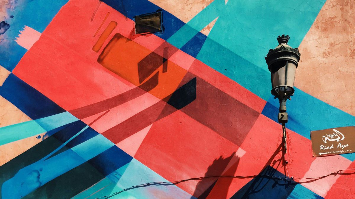 Eine Hausmauer ist mit geometrischen Formen in rot, türkis und blau geschmückt - sie wirkt wie ein Kunstwerk.