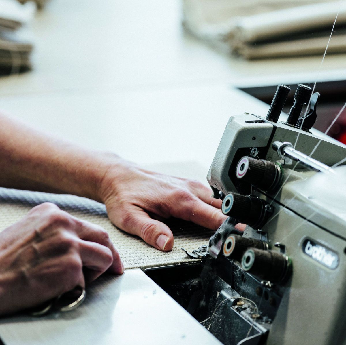 Die Hände einer Schneiderin bei der Arbeit an der Nähmaschine.