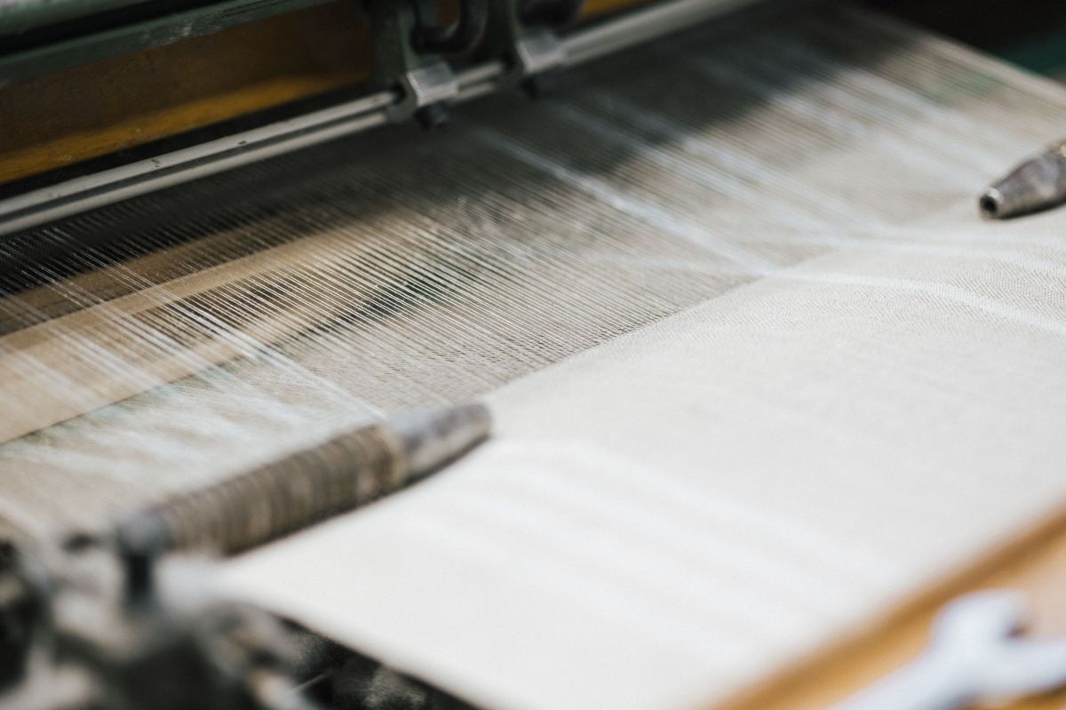 Eine Webmaschine produziert einen beigen Stoff