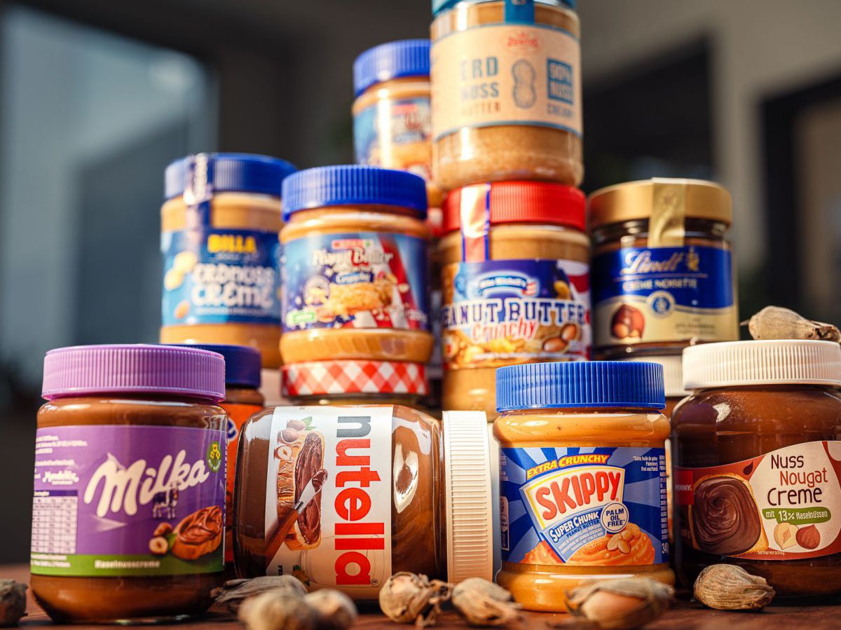 Ein Turm aus Nusscremes mit Markennamen wie Milka, Nutella, Lindt und Skippy.