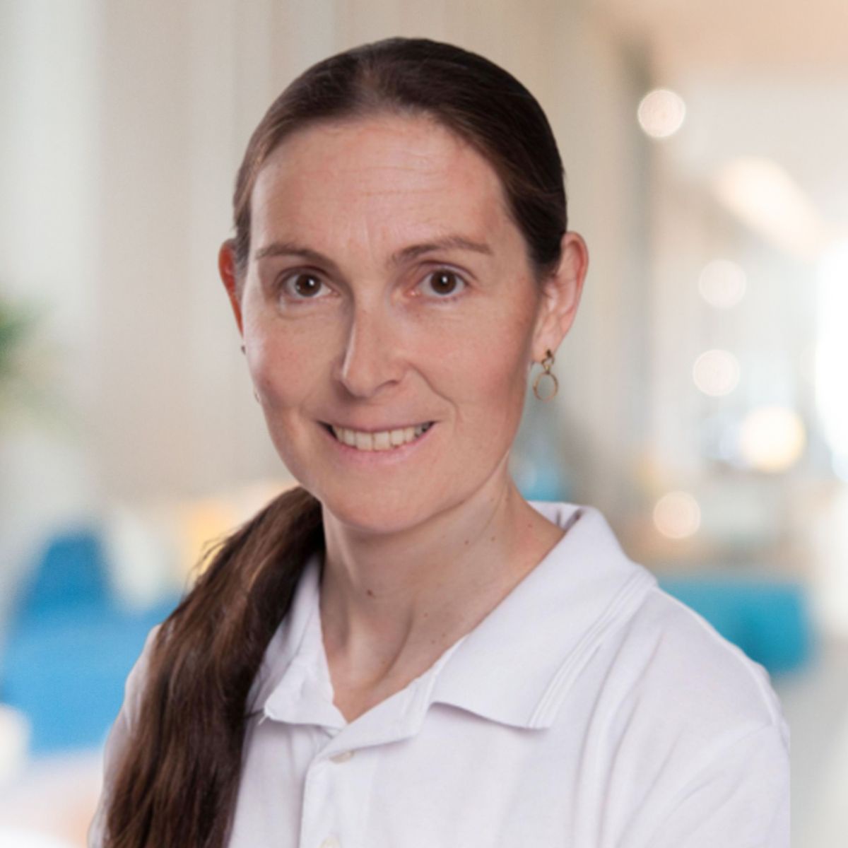 Eine Frau mit langen braunen Haaren und einem weißen Poloshirt.