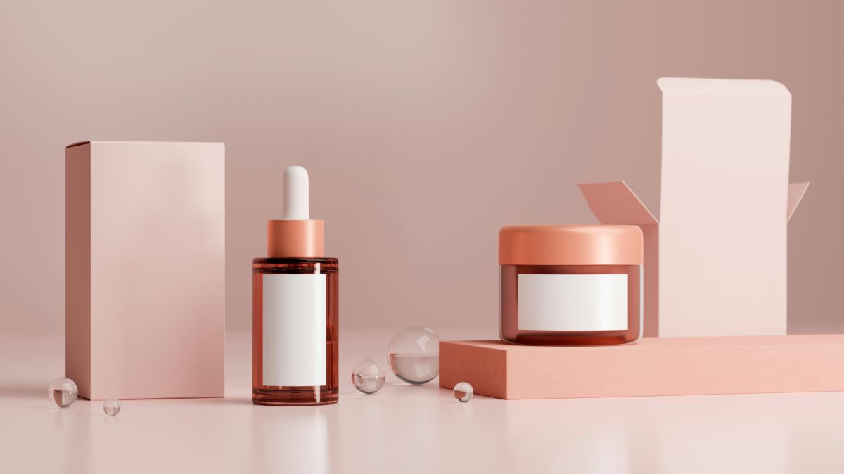 Eine Creme und ein Fläschchen Serum stehen auf einem Tisch neben ihren Verpackungen. Sie sind ohne Marke.