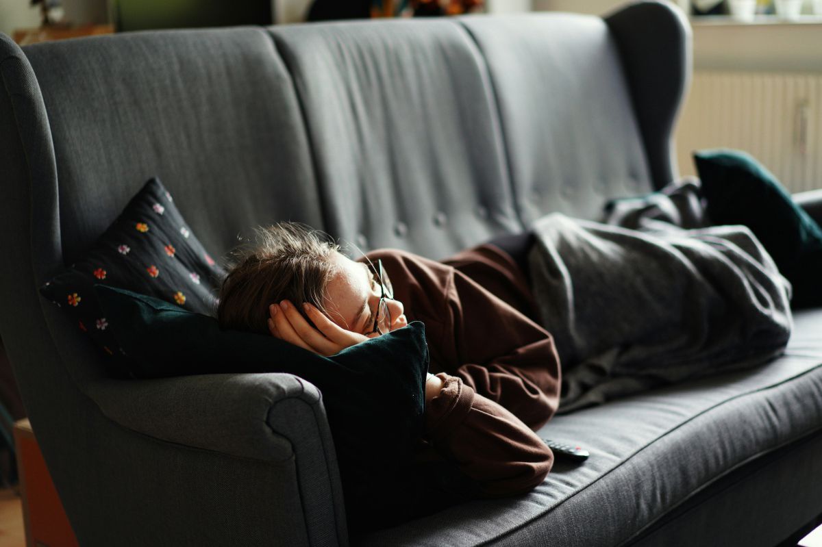 Eine Person liegt auf einem Sofa und hält ein Schläfchen.
