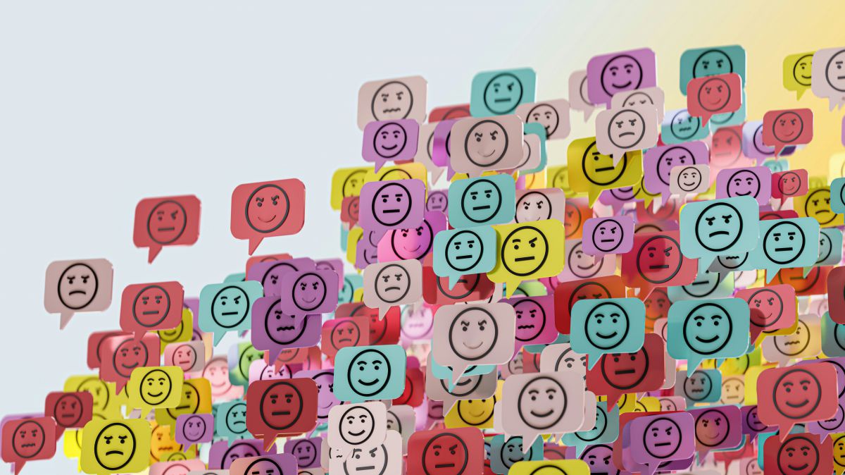 Eine Wand mit vielen bunten Post-Its auf denen Smileys mit unterschiedlichen Gesichtsausdrücken zu sehen sind.