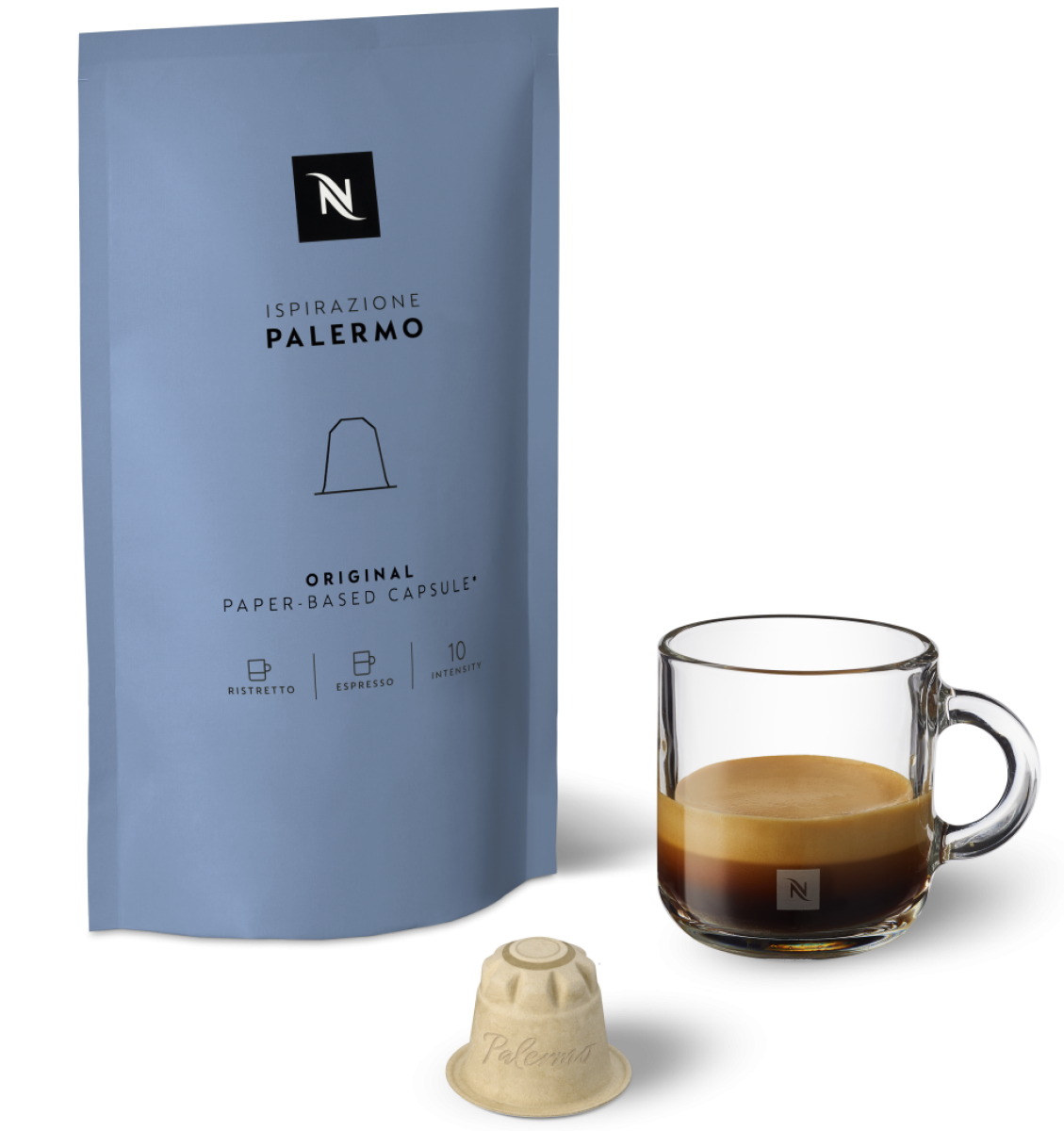 Eine Packung pflanzenbasierter Kaffekapseln der Sorte Palermo in einem taubenblauen Beutel, ein gläserner Becher, zu einem Drittel gefüllt mir frisch gebrühtem Kaffee, daneben eine der Kapseln.