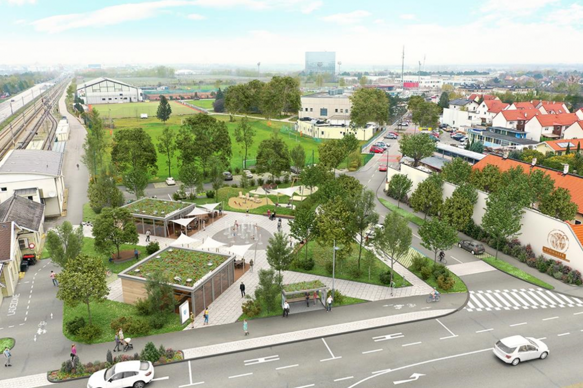 Der Platz ist kaum wiederzuerkennen: zwei kleinere Gebäude mit Dachbegrünung, mehrere Elemte mit Wiese und Bäumen über den Platz verteilt, im Zentrum gepflastert aber mit Wasserfontänen zur Abkühlung im Sommer.