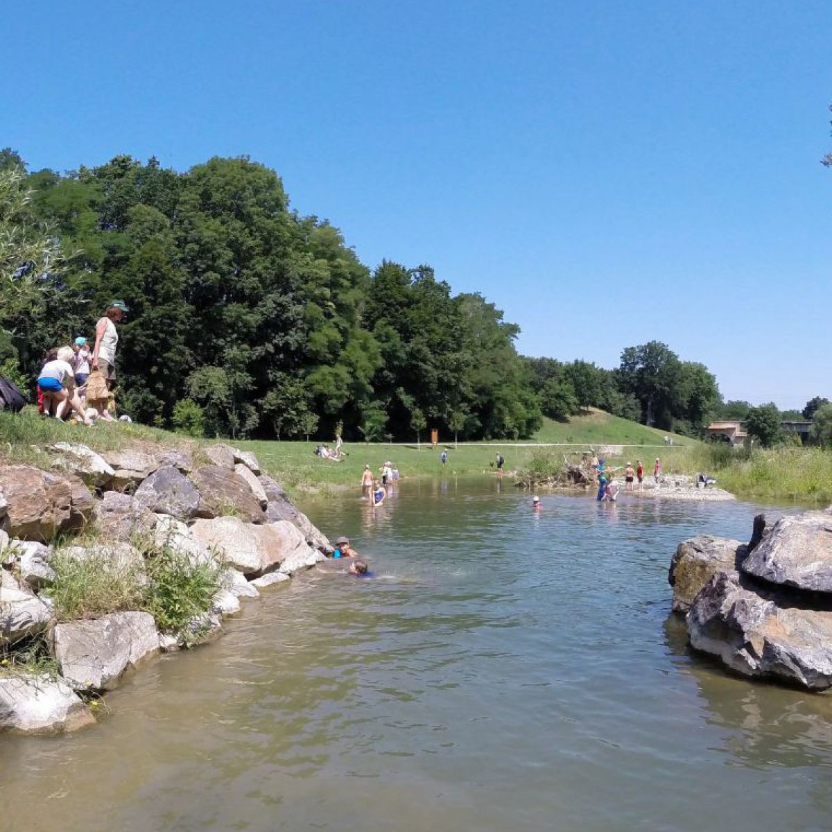 Badende Menschen am Michelbach bei den Buhnen, das sind Bauwerke aus großen Steinen, die vom Ufer in den Fluss
hineinragen, was das Wasser an diesen Stellen tiefer macht.
